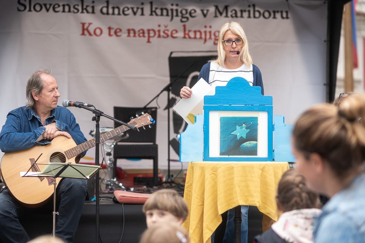 Pripovedovanje kamišibaja Agica, mala čarovnica ob spremljavi kitare pred otroki na Grajskem trgu v Mariboru, 2020