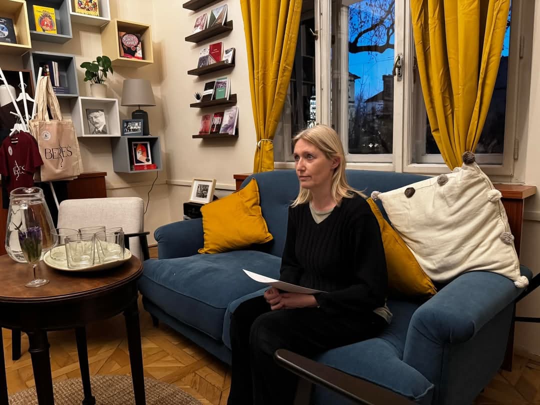 Udeleženka z listi v rokah sedi na modrem kavču, Glas avtoric, DSP Ljubljana, 8. 3. 2025